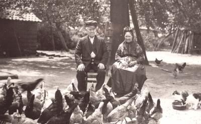 Foto van man en vrouw op het erf met kippen en katten